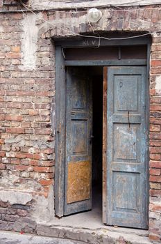 Ancient grunge masonry house wooden doors and red brick wall background.