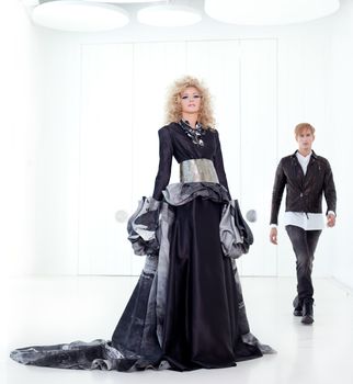 Black haute couture retro futurist couple in modern white hall with vampire inspiration