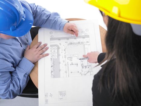 Two architects with hard hats and plan on meeting in office