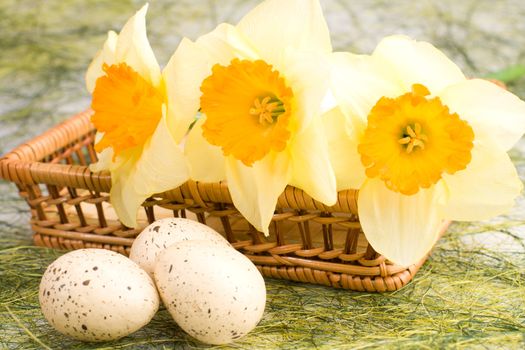 Decorated speckled easter eggs with a bunch of daffodils in the woven basket