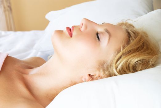 profile of a beautiful young blond woman sleeping peacefully in her bed at home