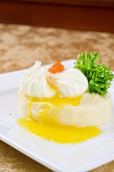 poached eggs in a nest of mashed potatoes with greens and caviar