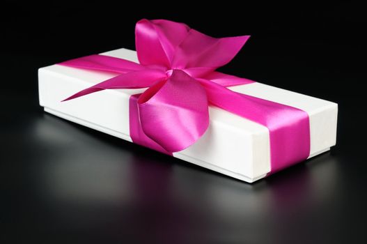Gift box with a big pink bow. On a dark background.