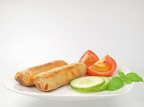 plate of homemade spring rolls with cucumber and tomato slice