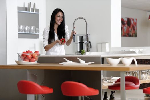 Beautiful young woman preparing food in her modern kitchen at home