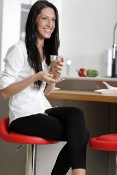 Attractive young woman taking a coffee break in her kitchen