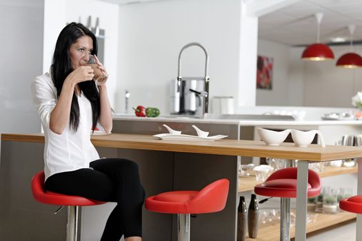 Attractive young woman taking a coffee break in her kitchen