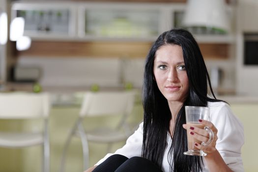 Attractive young woman taking a coffee break in her kitchen