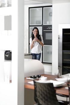 Beautiful young woman relaxing in her elegant white kitchen