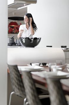 Beautiful young woman relaxing in her elegant white kitchen