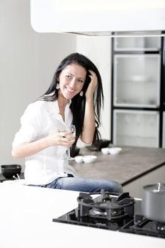 Beautiful young woman relaxing in her elegant white kitchen