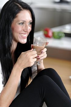 Attractive young woman taking a coffee break in her kitchen