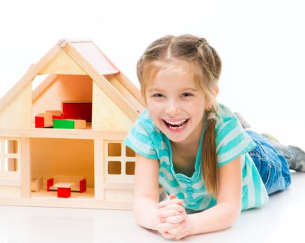 smiling girl with a toy house lying on the floor