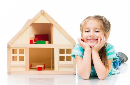 girl with a toy house lying on the floor