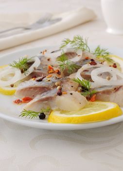 Slices of salted herring fillet with onion, lemon and spices

