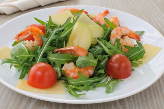 Salad with arugula and cherry tomatoes with shrimp, slices of apple and parmesan