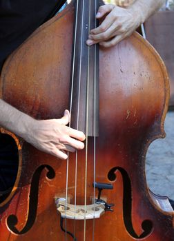 Hands playing a brown wooden bass