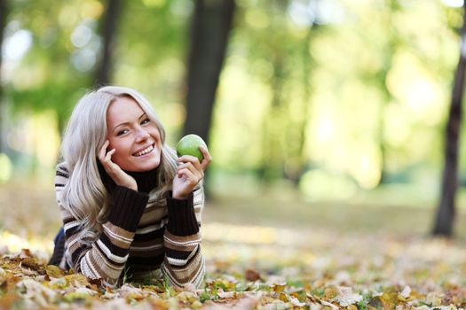 woman with green apple in autumn park
