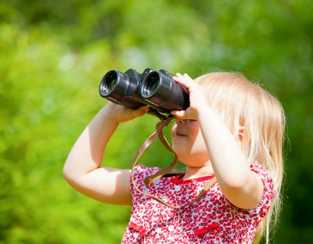 Little girl looking through binoculars outdoor
