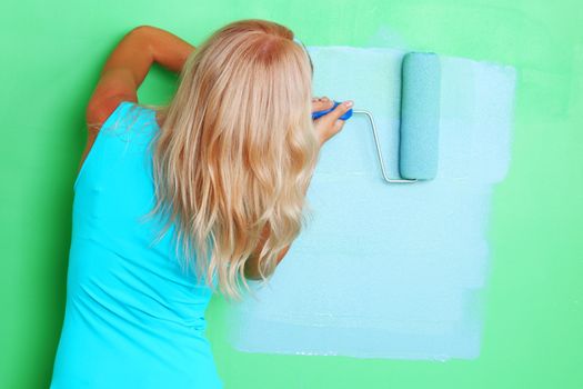woman paints the wall roller