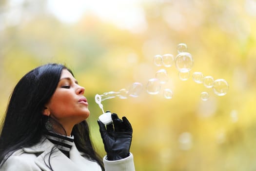 autumn woman blow bubbles portrait in park