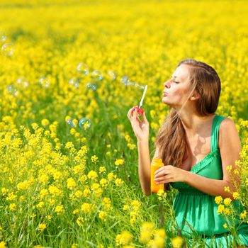 woman start soap bubbles on yellow flower field