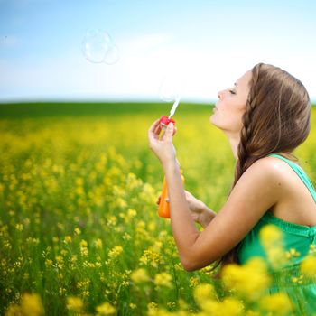 woman start soap bubbles on yellow flower field