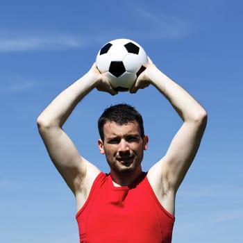 handsome man with ball and blue sky in summer