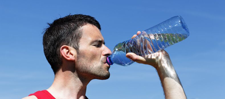 handsome man drinking water in blue sky