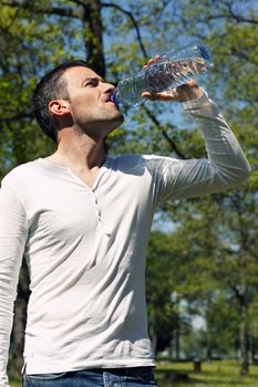 beautiful man drinking water in a park