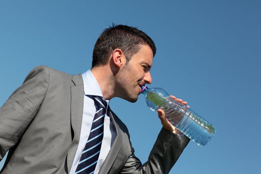young man drinking water in blue sky 