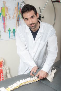 Manual, physio and kinesio therapy techniques performed by a male physiotherapist on a training plastic spine and a female patient