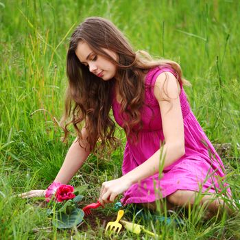 girl grow flower on green field