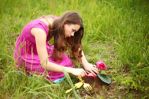 girl grow flower on green field