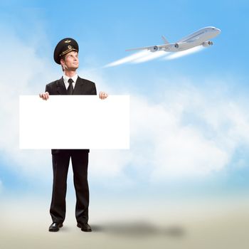 pilot in the form of holding an empty billboard on the background of sky and flying plane, place for text