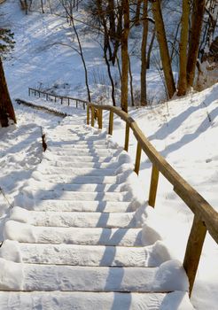 Oak stairs and handrail on steep mountain slope covered with snow in winter.