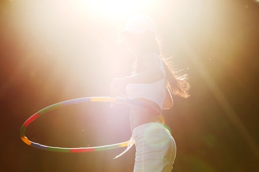 woman rotates hula hoop on nature background
