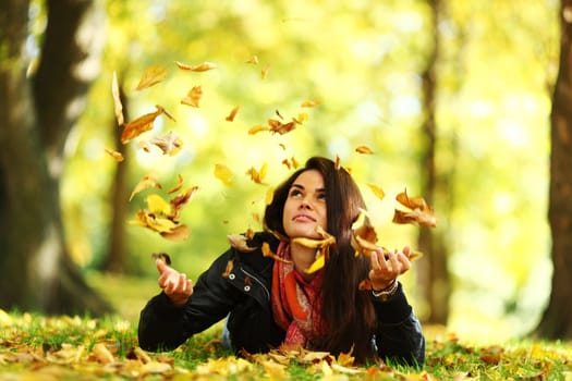 woman drop up leaves in autumn park