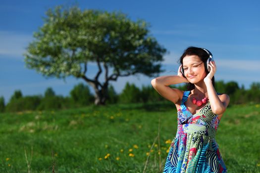 Young woman with headphones listening to music on field