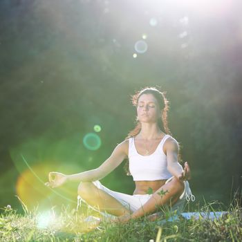 yoga woman on green grass lotus pose in sunrise light