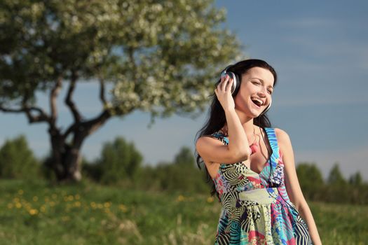 Young woman with headphones listening to music on field