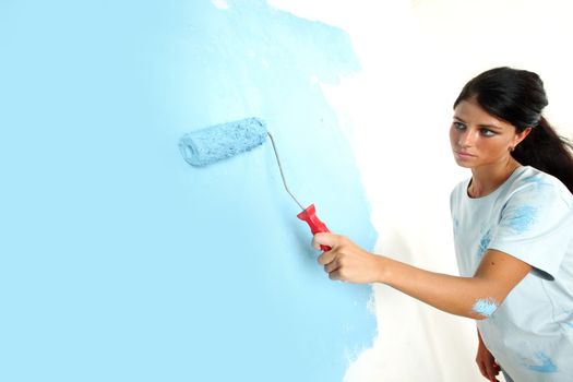roller in woman hand paint on the wall