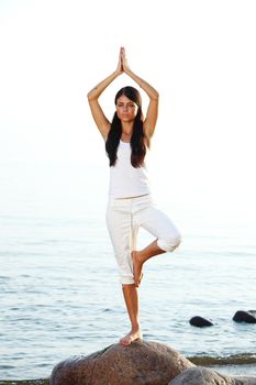 Young woman practicing yoga  near the ocean