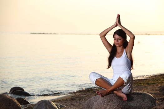 Young woman practicing yoga  near the ocean