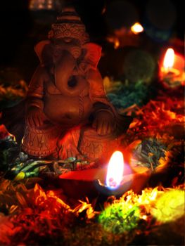 An idol of lord ganesh being worshipped with a traditional lamp and flowers.                               