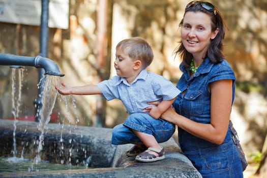 Mother and her little son outdoors in city near fountain