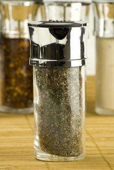 dry sage in a glass jar on different spices background over wooden mat