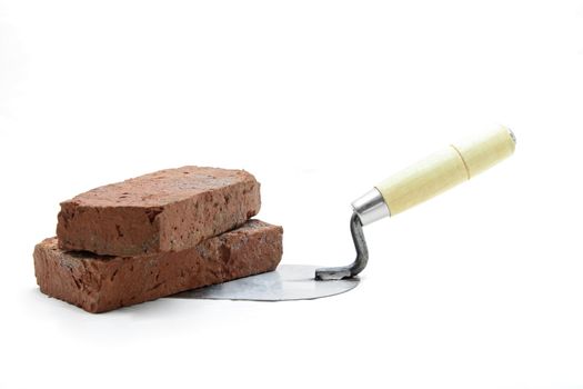 Studio shot of construction lute trowel with red brick isolated on white
