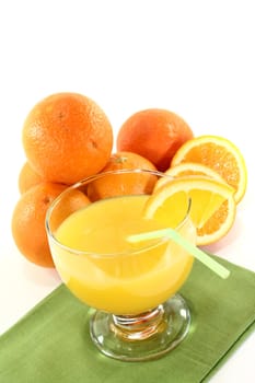 glass of freshly squeezed orange juice with orange halves on a light background