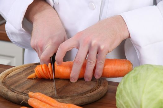 chef preparing lunch and cutting carrot with knife
